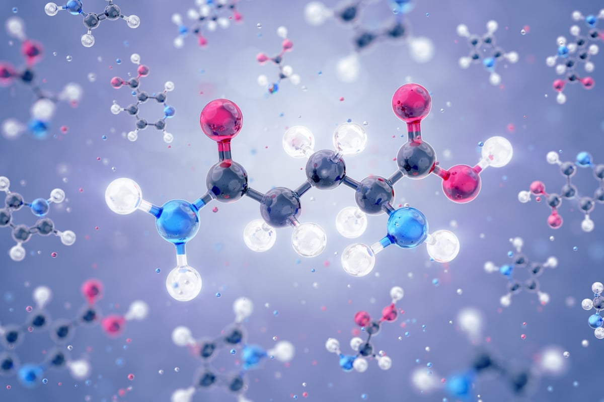 A 3D model of the L-Glutamine amino acid, depicted as a schematic molecular structure, freely levitating among other organic substances
